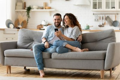 Deux personnes vendant leur bien immobilier sans l'aide d'une agence sur un canapé.